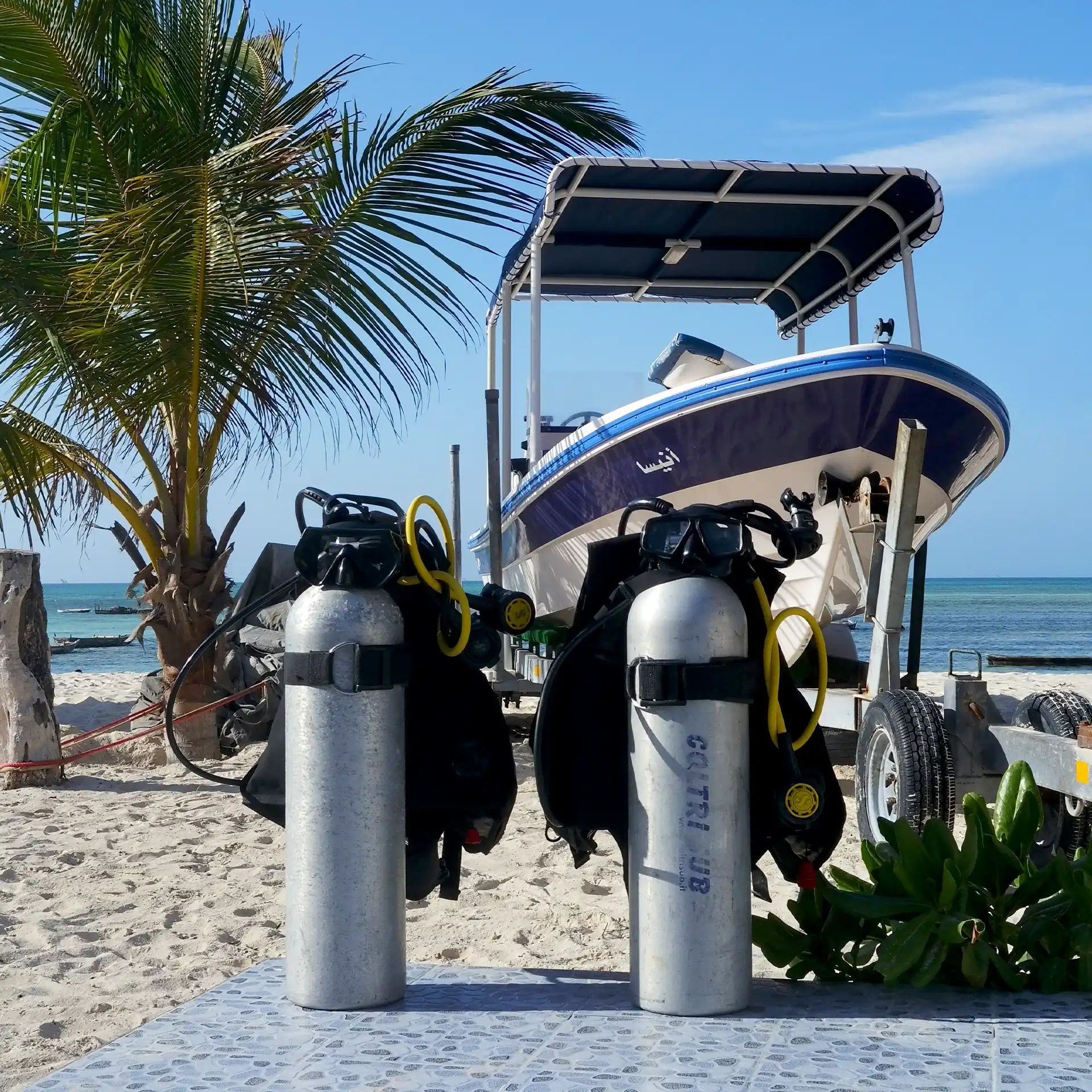 Scuba tanks and gear set up in front of a fiberglass dive boat parked on Nungwi Beach, Zanzibar