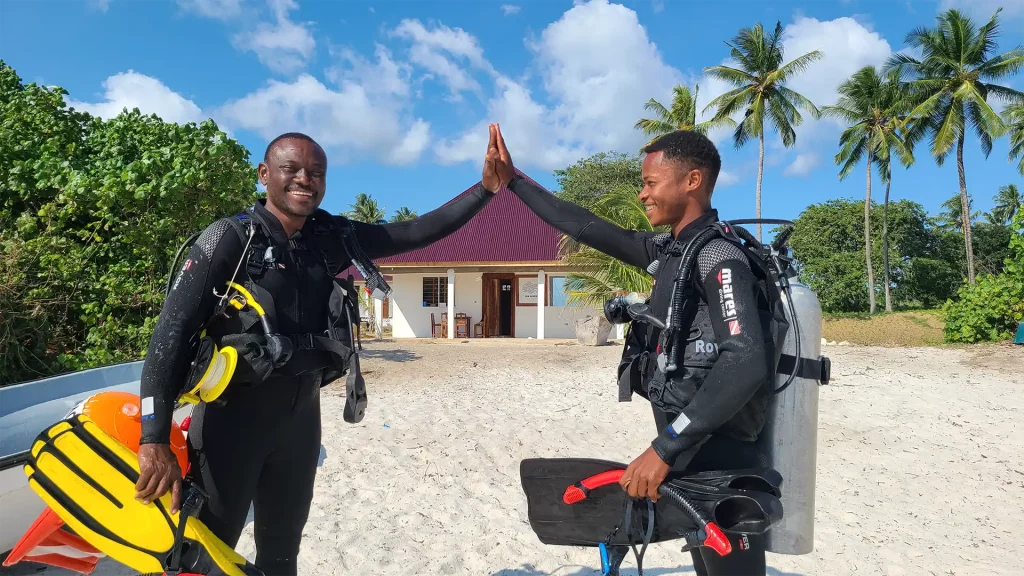 PADI dive instructor giving a high-five to a team member in front of the dive center on Pemba Island