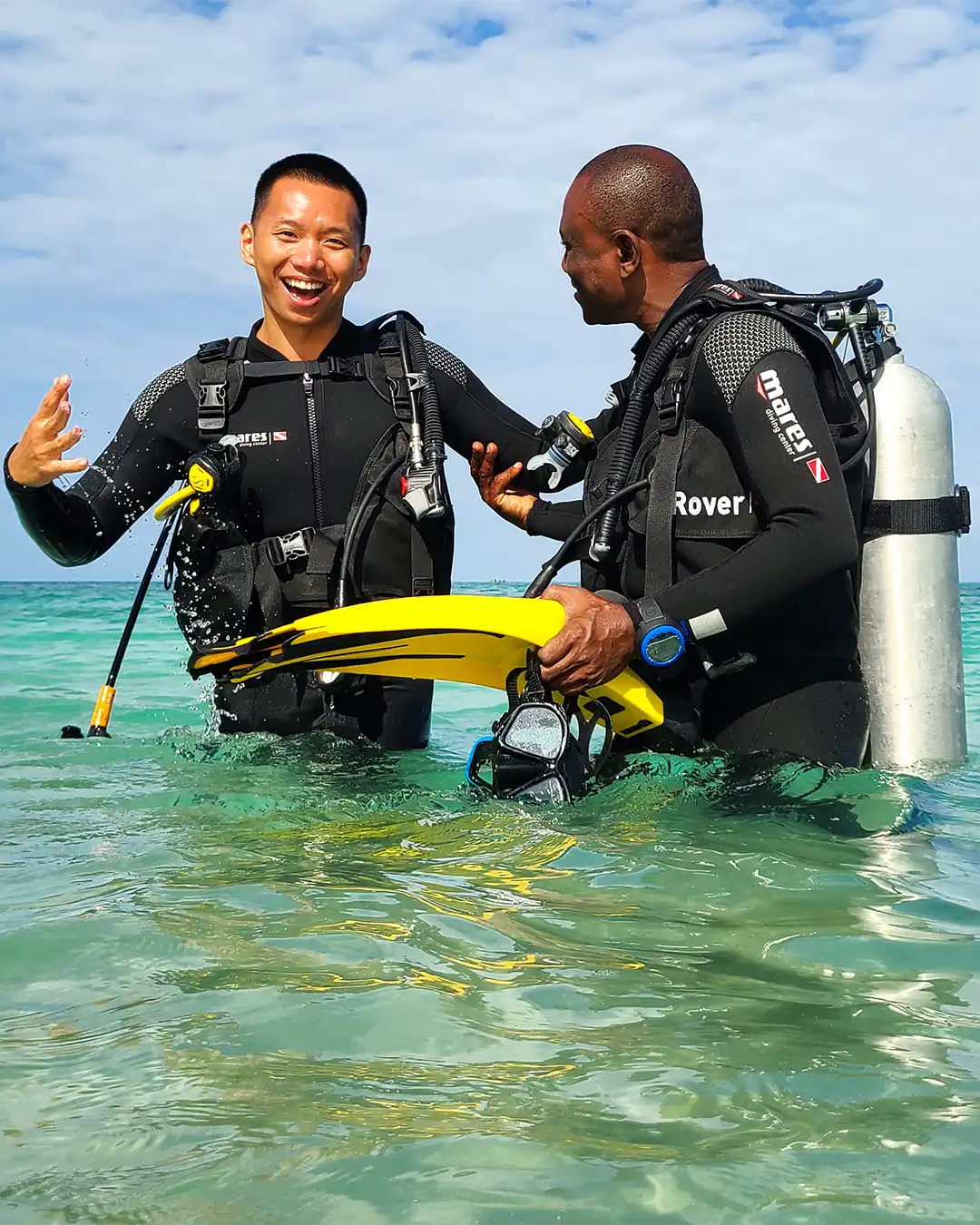 PADI dive instructor training with a guest in the shallow ocean over a vibrant coral reef in Pemba Island, Tanzania