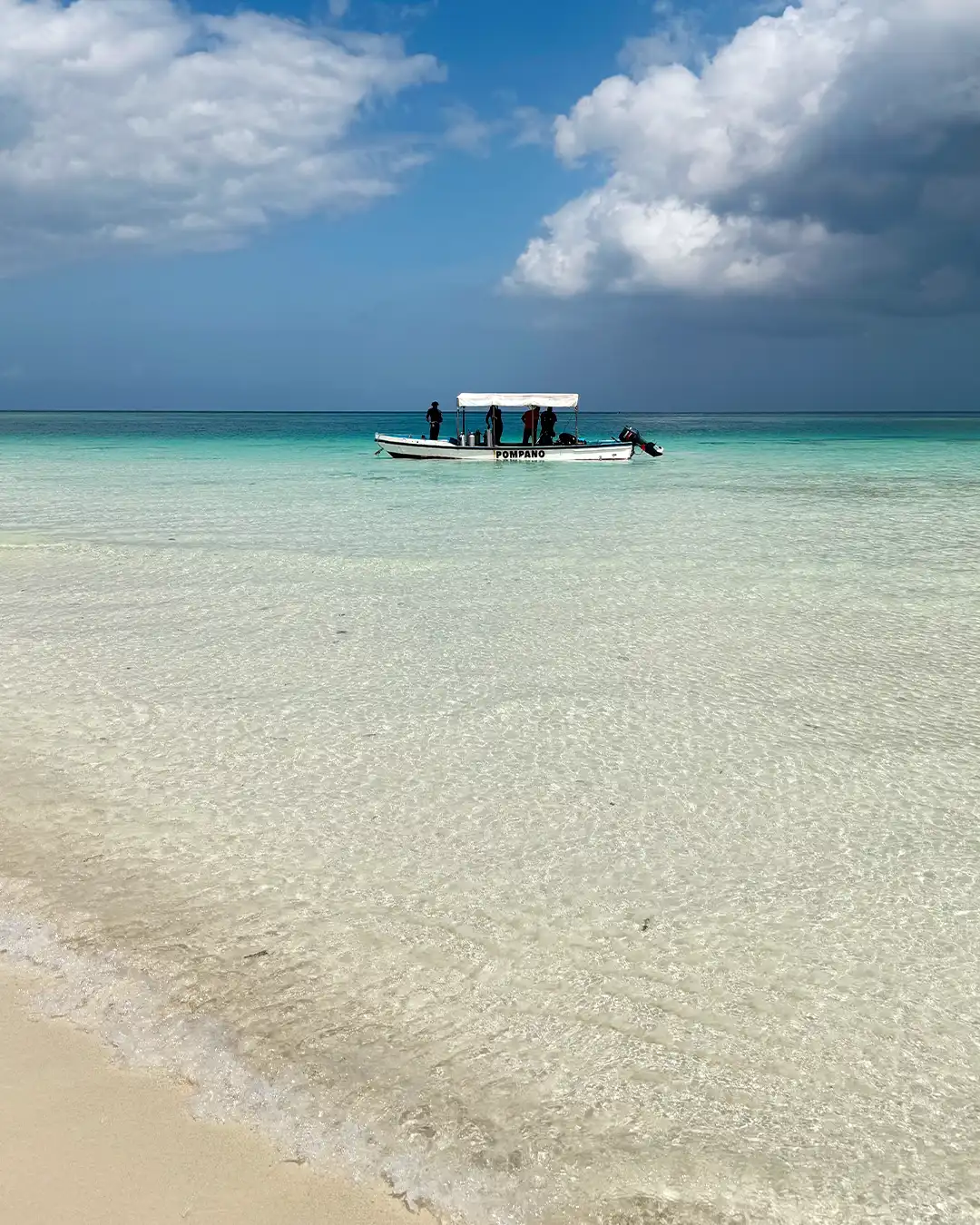 Traditional dive boat anchored off a white sand bank in crystal-clear turquoise water during a surface interval on Pemba Island